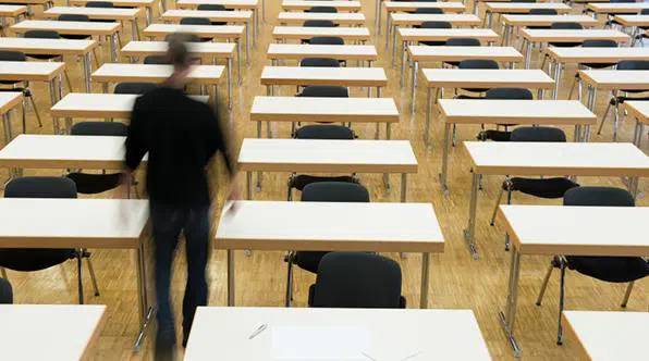 Several chairs aligned in a room and a man walking among them