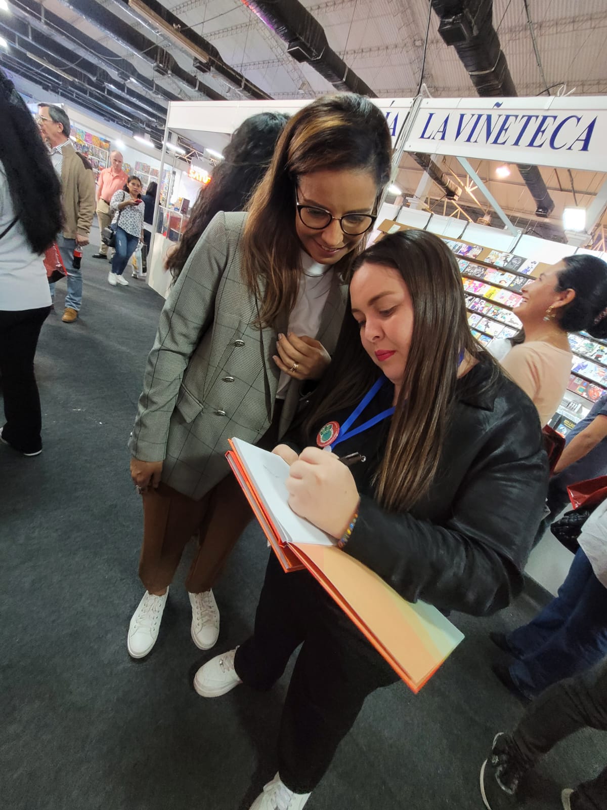 dos mujeres paradas autografiando un libro