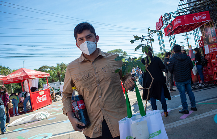 Un participante con una planta, una Coca-Cola retornable y bolsas ecológicas