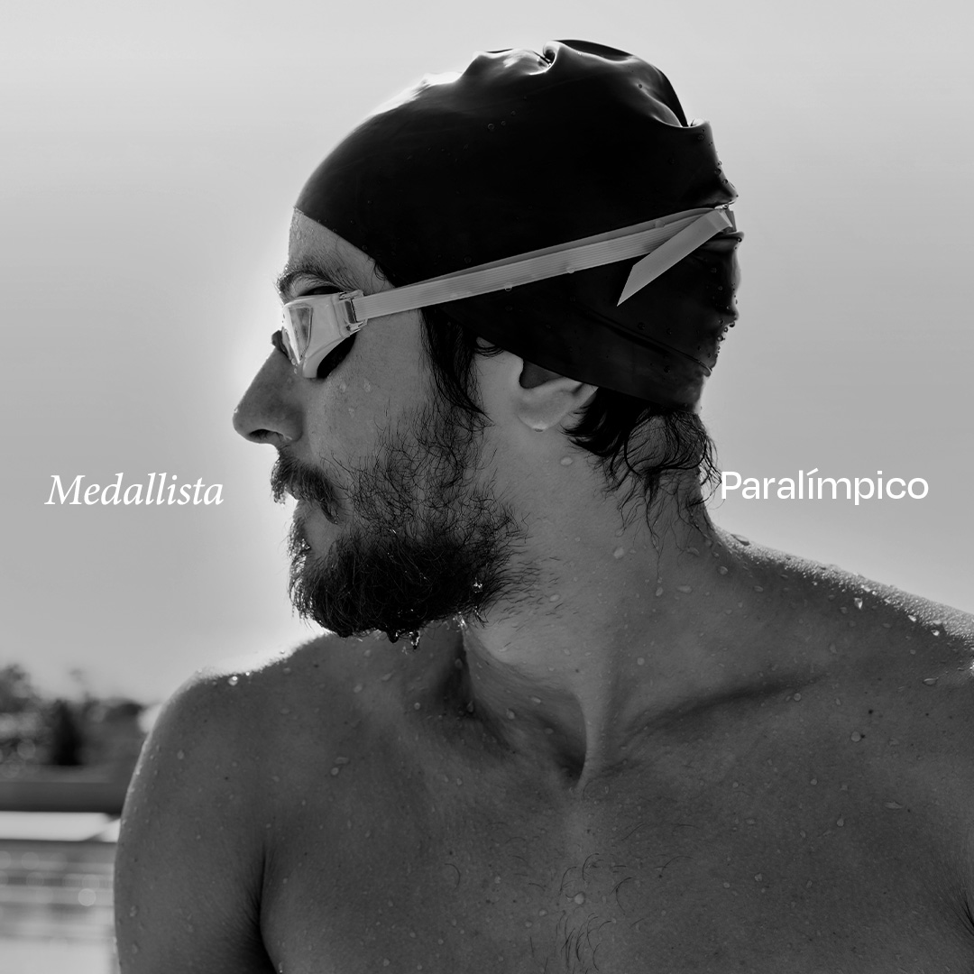 Retrato en blanco y negro de Douglas Matera, nadador paralímpico, mirando hacia la izquierda con las palabras 'Medallista Paralímpico' escritas alrededor. Lleva un gorro de natación y gafas, y tiene gotas de agua en los hombros.