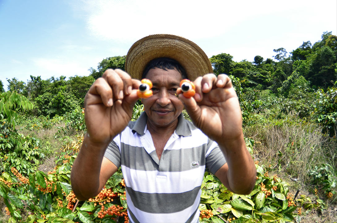 Homem segurando frutas na frente do rosto.