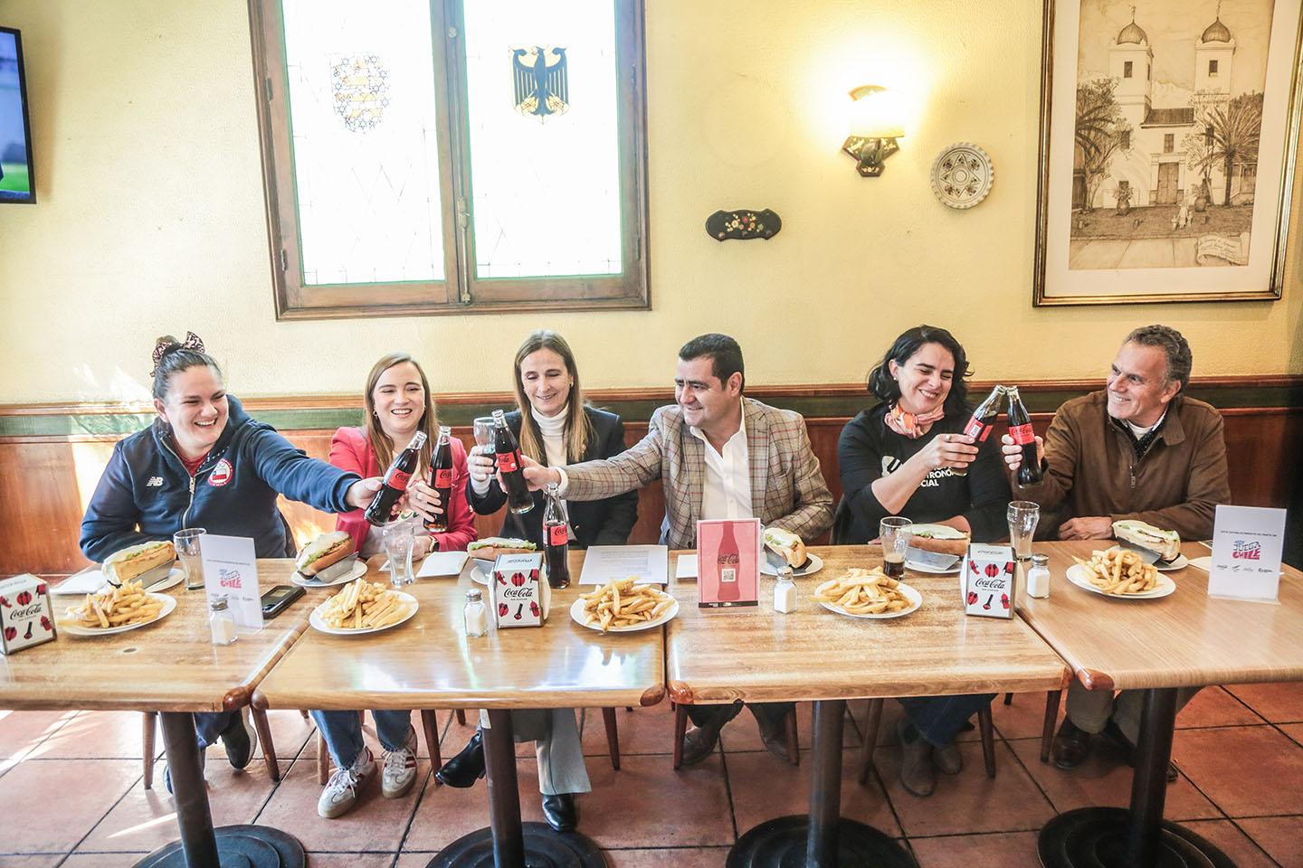 Imagen de un grupo de personas brindando con Coca-Colas