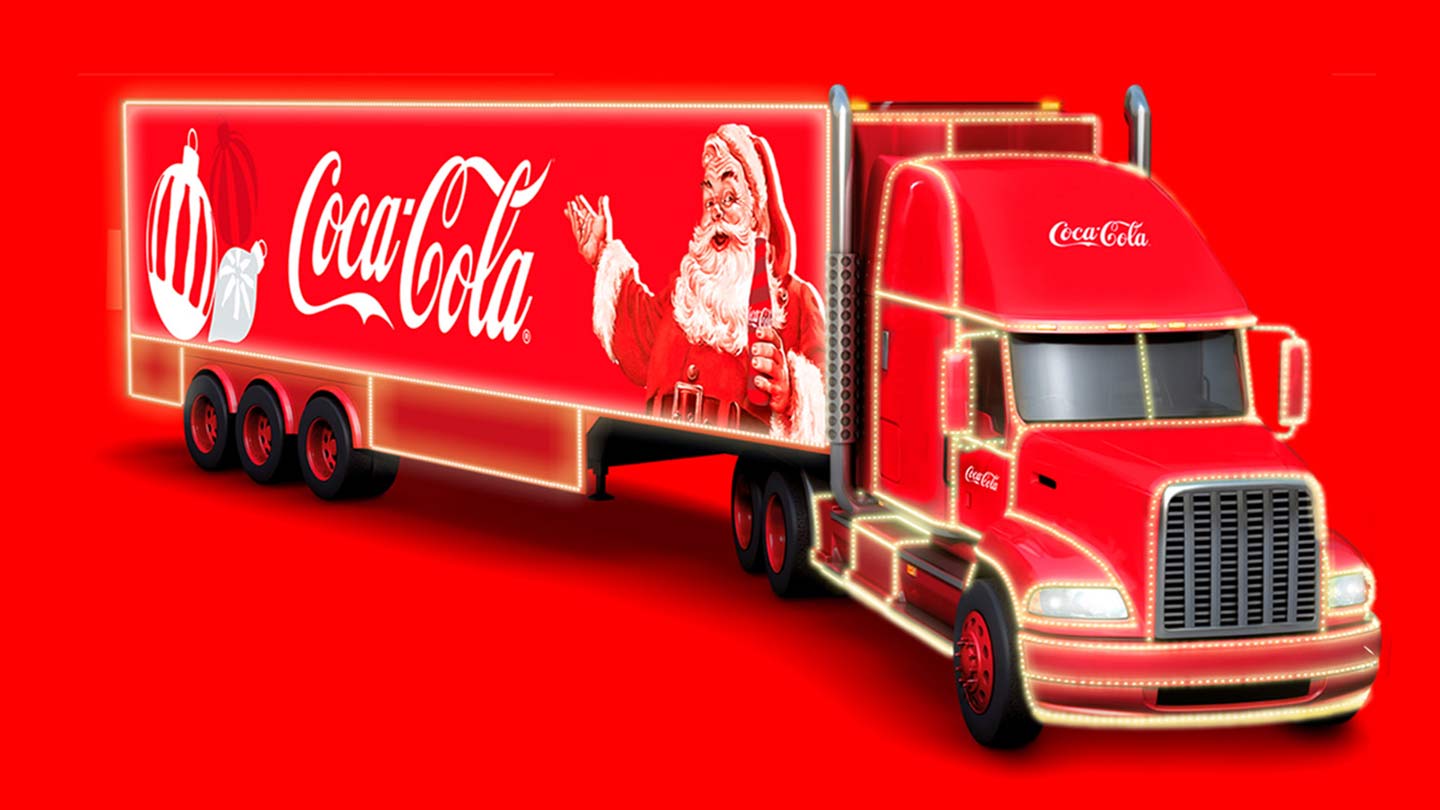 Un camión rojo brillante decorado con luces navideñas y una imagen del Viejito Pascuero sosteniendo una Coca-Cola.