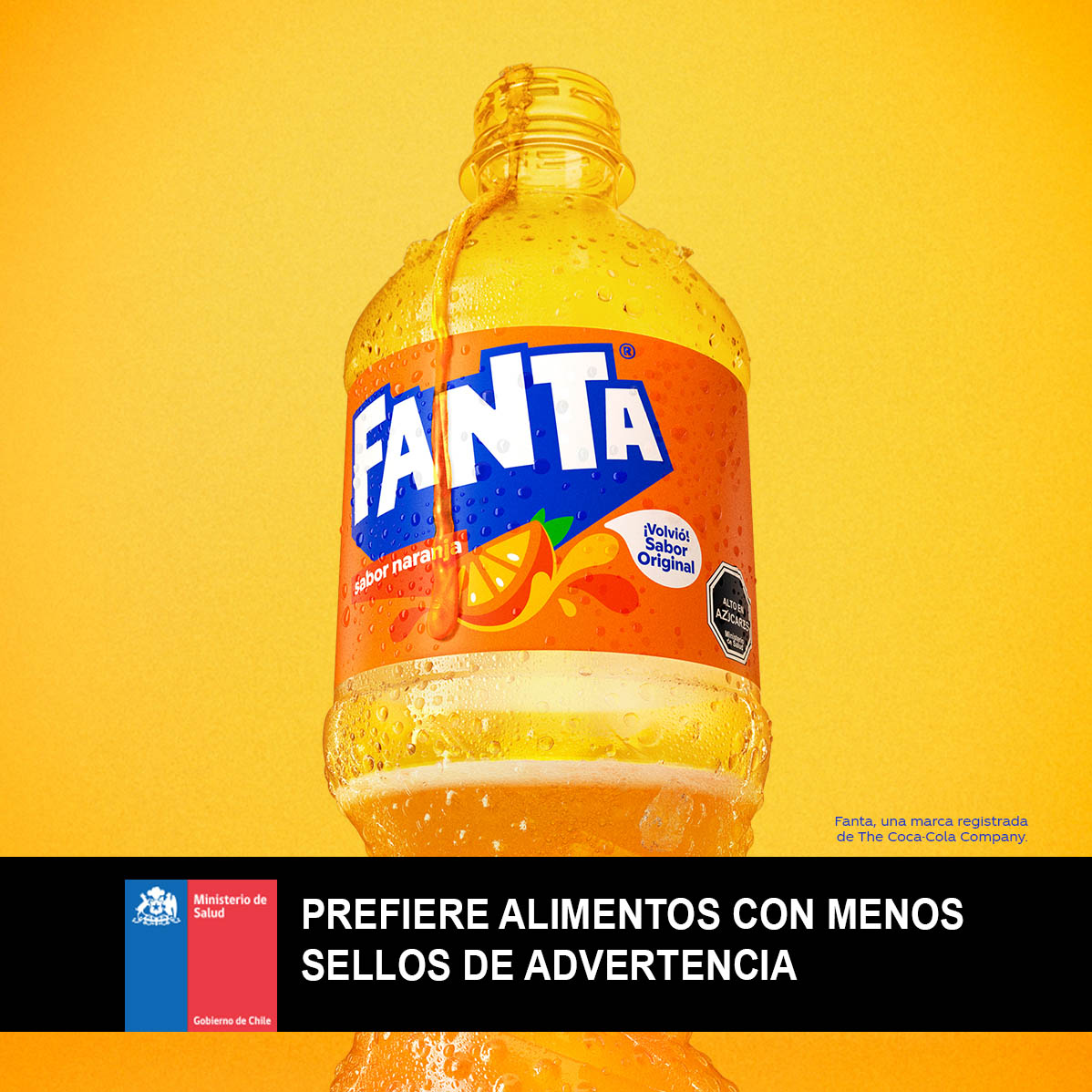 Botella fría de Fanta sabor Naranja destapada sobre un fondo naranja claro.