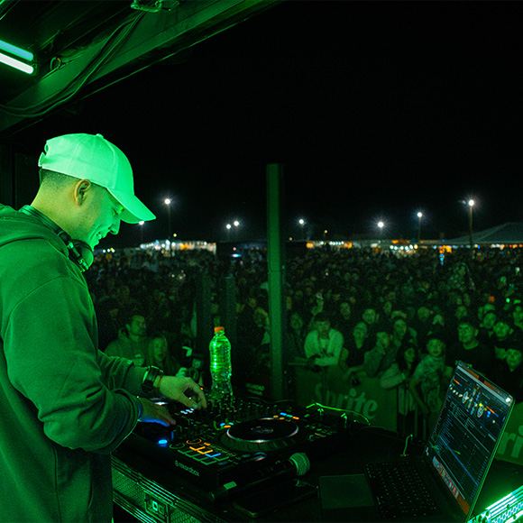 DJ poniendo música en el concierto Sprite RefresCAR con luces verdes frente a una multitud.