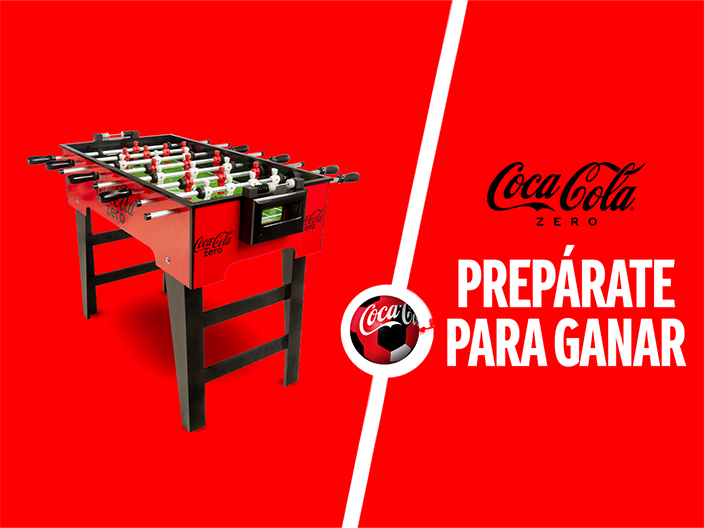 Fotografía de un futbolín sobre un fondo rojo. A la derecha el logo de "Coca-Cola Zero" y debajo la frase "Prepárate para ganar"