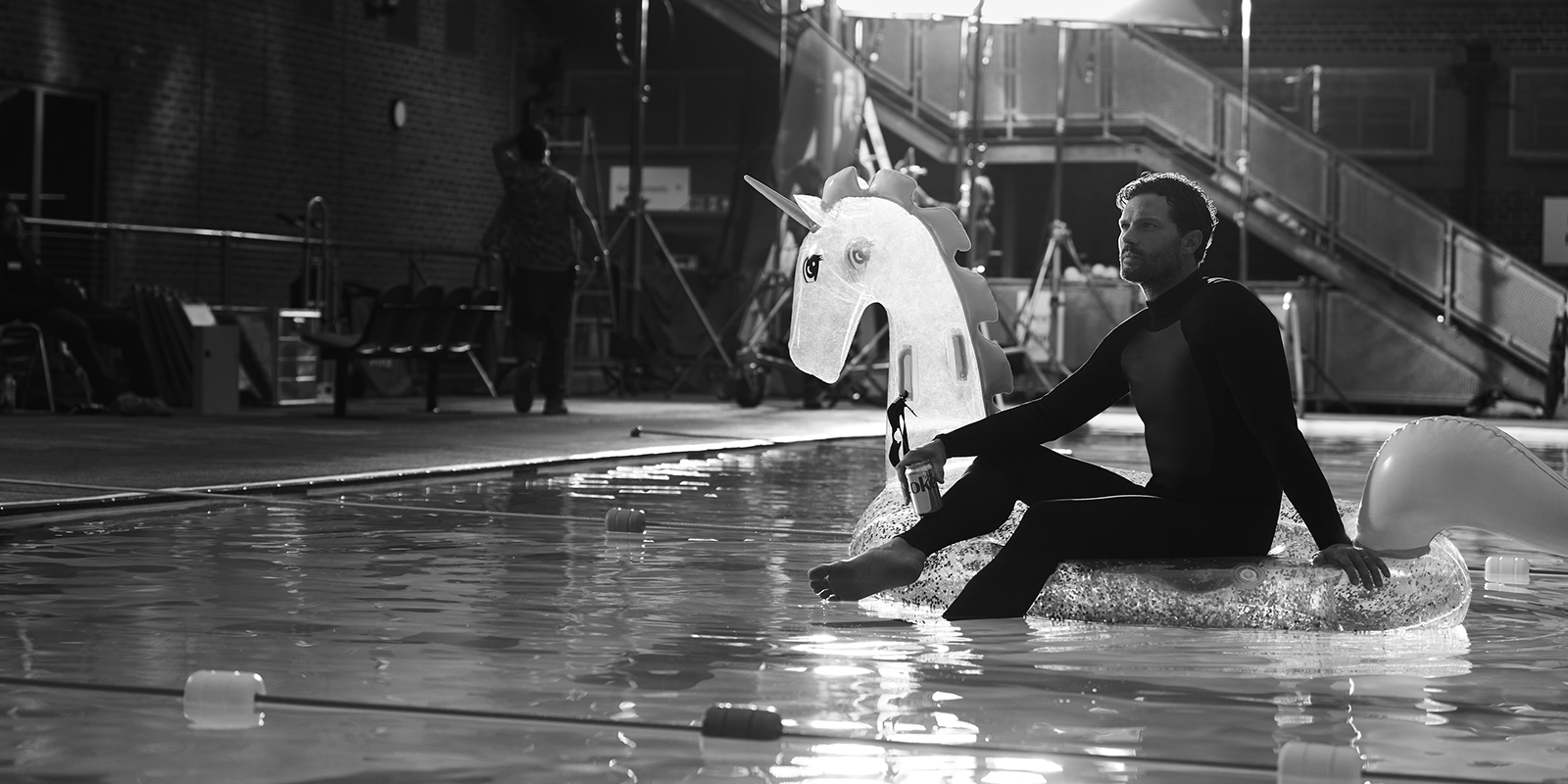 man sitting in a pool on an inflatable, holding a diet-coke