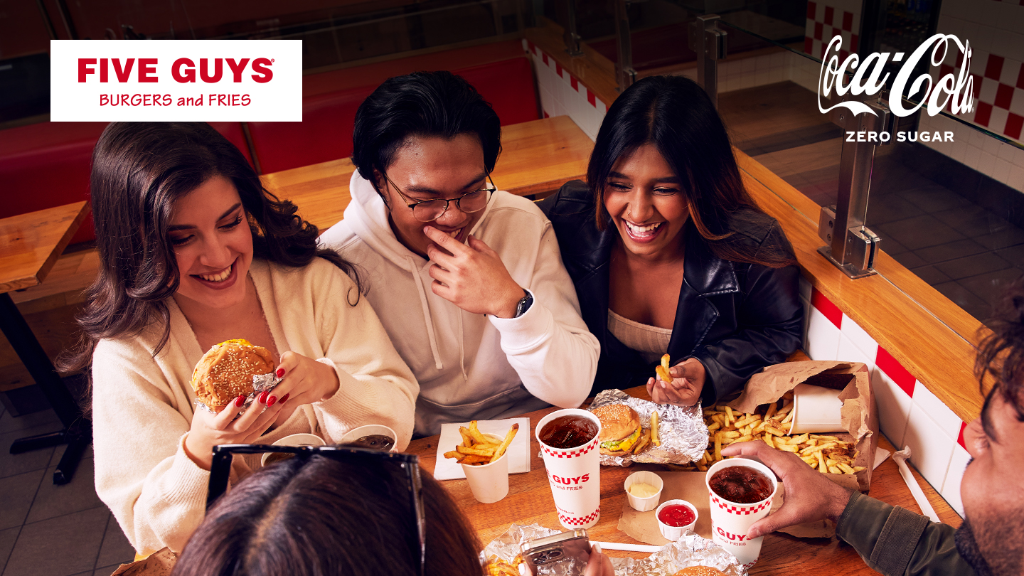 a group of friends enjoying a five guys burger and a coca-cola zero sugar