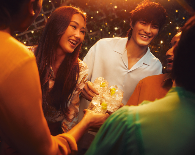 Friends outside standing in a circle, toasting with Schweppes cocktails