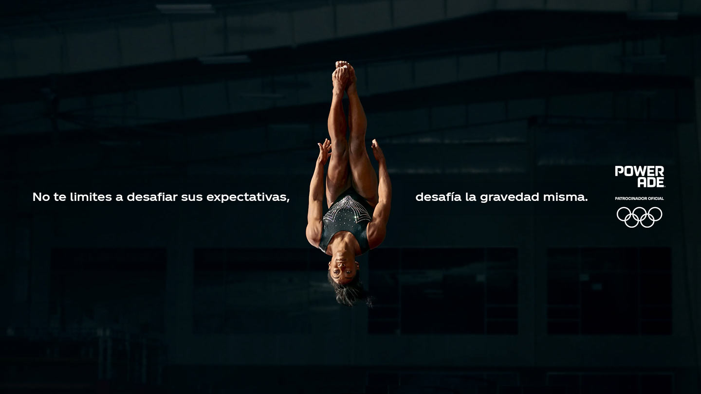 Gimnasta Olímpica dando vueltas en el aire. Con el texto: No te limites a desafiar sus expectativas, desafía la gravedad misma.