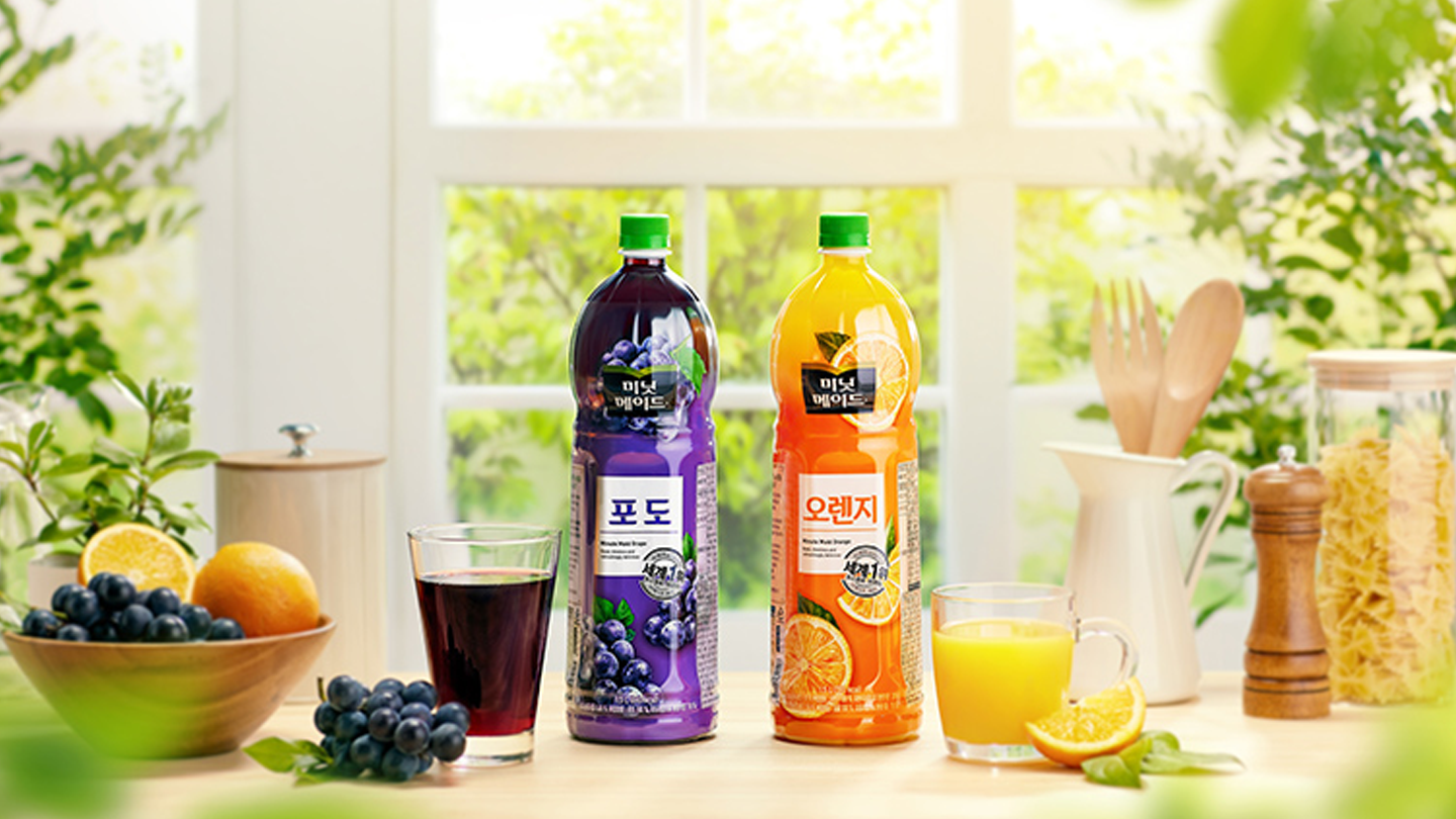 주방을 배경으로 미닛메이드 오렌지와 미닛메이드 포도 제품이 정면으로 가운데에 크게 위치해 있고, 양 옆에는 각 제품이 따라진 컵이 위치해 있다. 