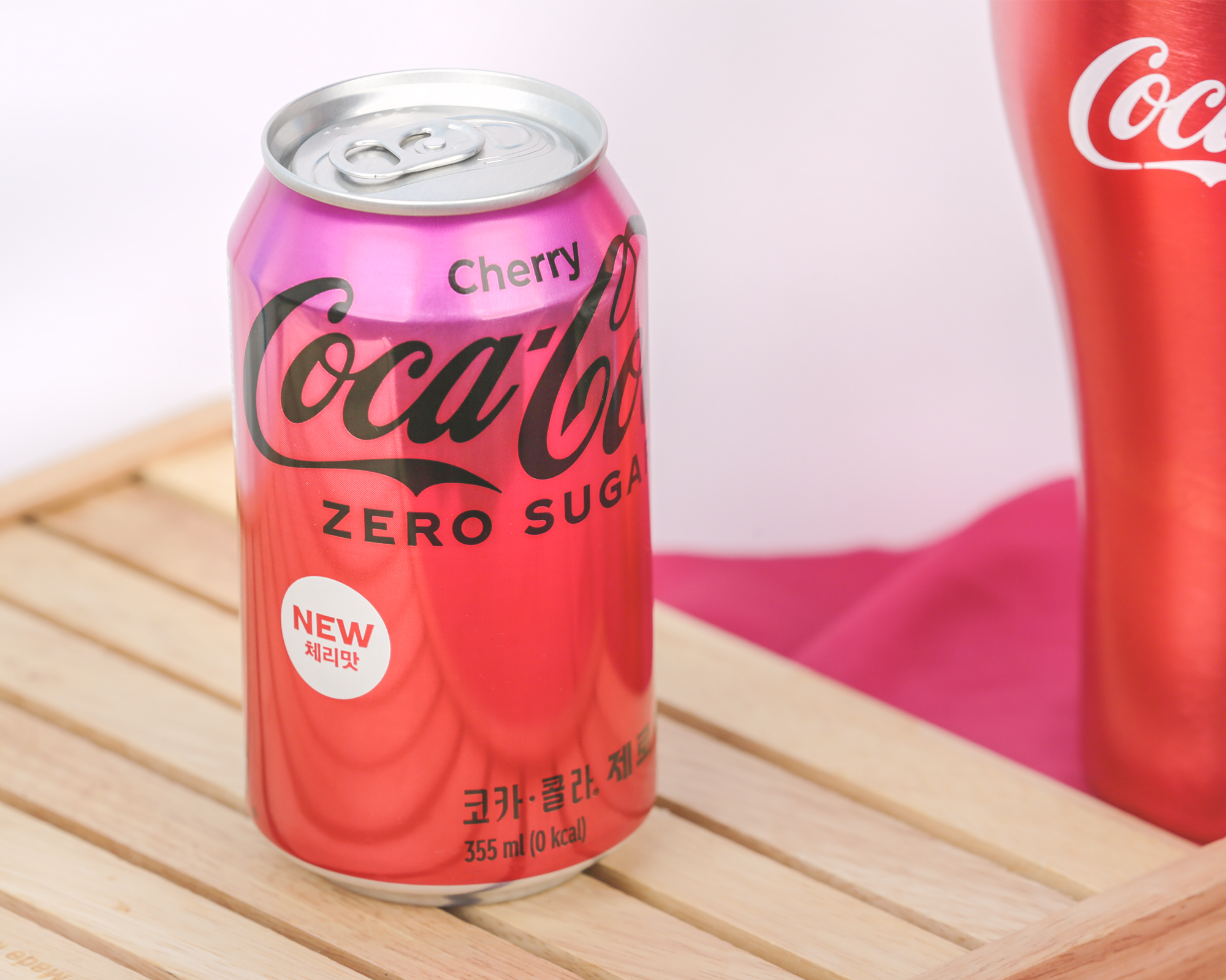 코카-콜라 제로 체리가 나무 받침대 위에 놓여 있다. 새로운 패키지 디자인에 ‘NEW 체리맛’이라는 글자가 새겨져 있다.
