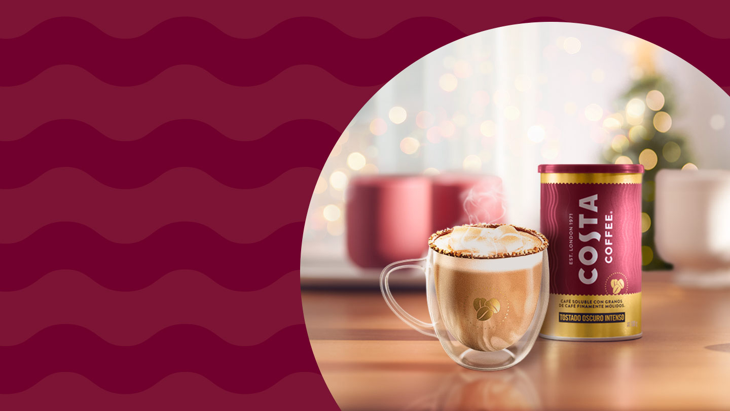 Fotografía de un envase de Costa Coffee Molído y una taza de café. En el fondo y fuera de foco, un árbol de navidad y decoración navideña.