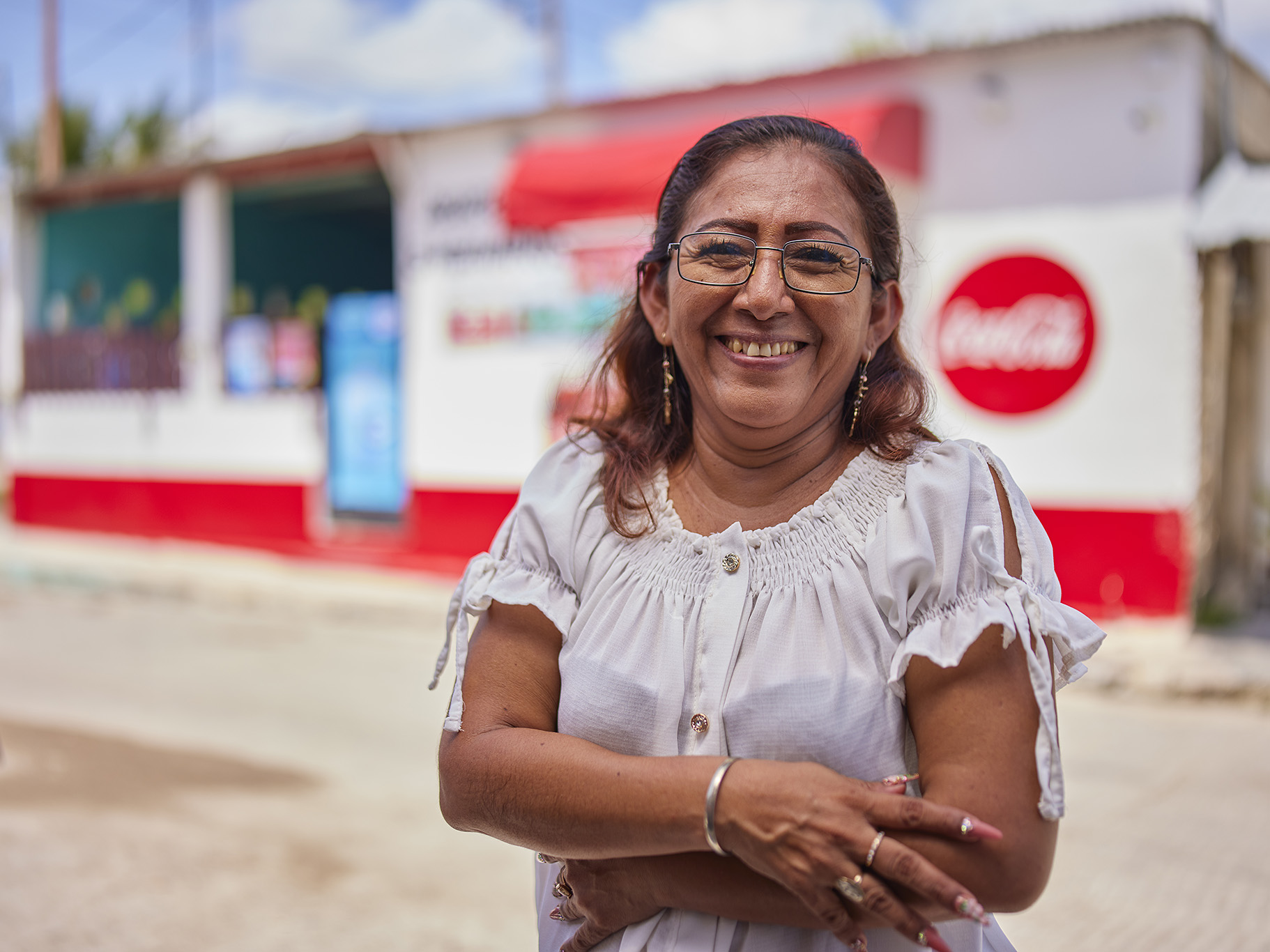 Imagen de una señora en primer plano y en el fondo un logo de Coca-Cola