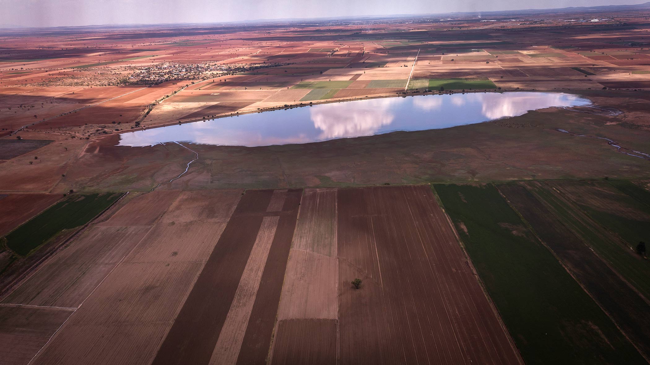 imagen de un paisaje en donde se puede ver parte de tierra, pastizales y un lago