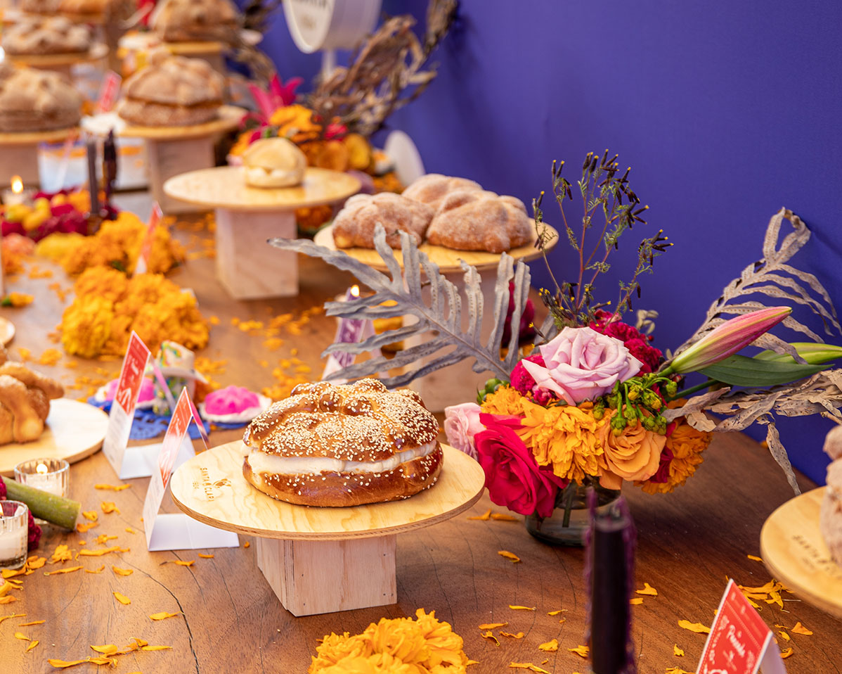 Mesa con diferentes preparaciones dulces. La mesa está decorada con diferentes flores  de muchos colores y pétalos.