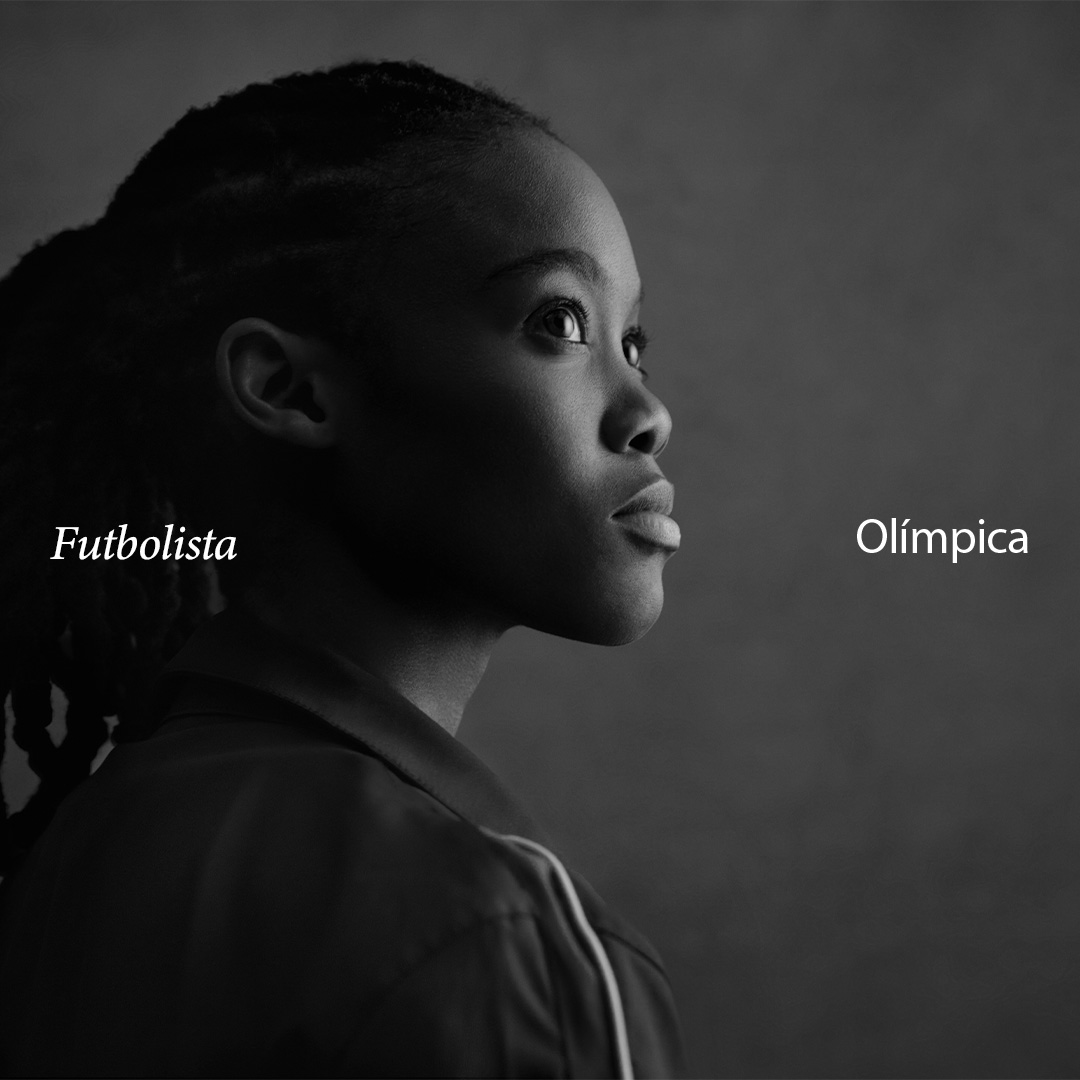 Retrato en blanco y negro de Linda Motlhalo, futbolista olímpica, mirando hacia la derecha con las palabras 'Futbolista' y 'Olímpica' escritas alrededor. Lleva una chaqueta deportiva y luce una expresión enfocada.