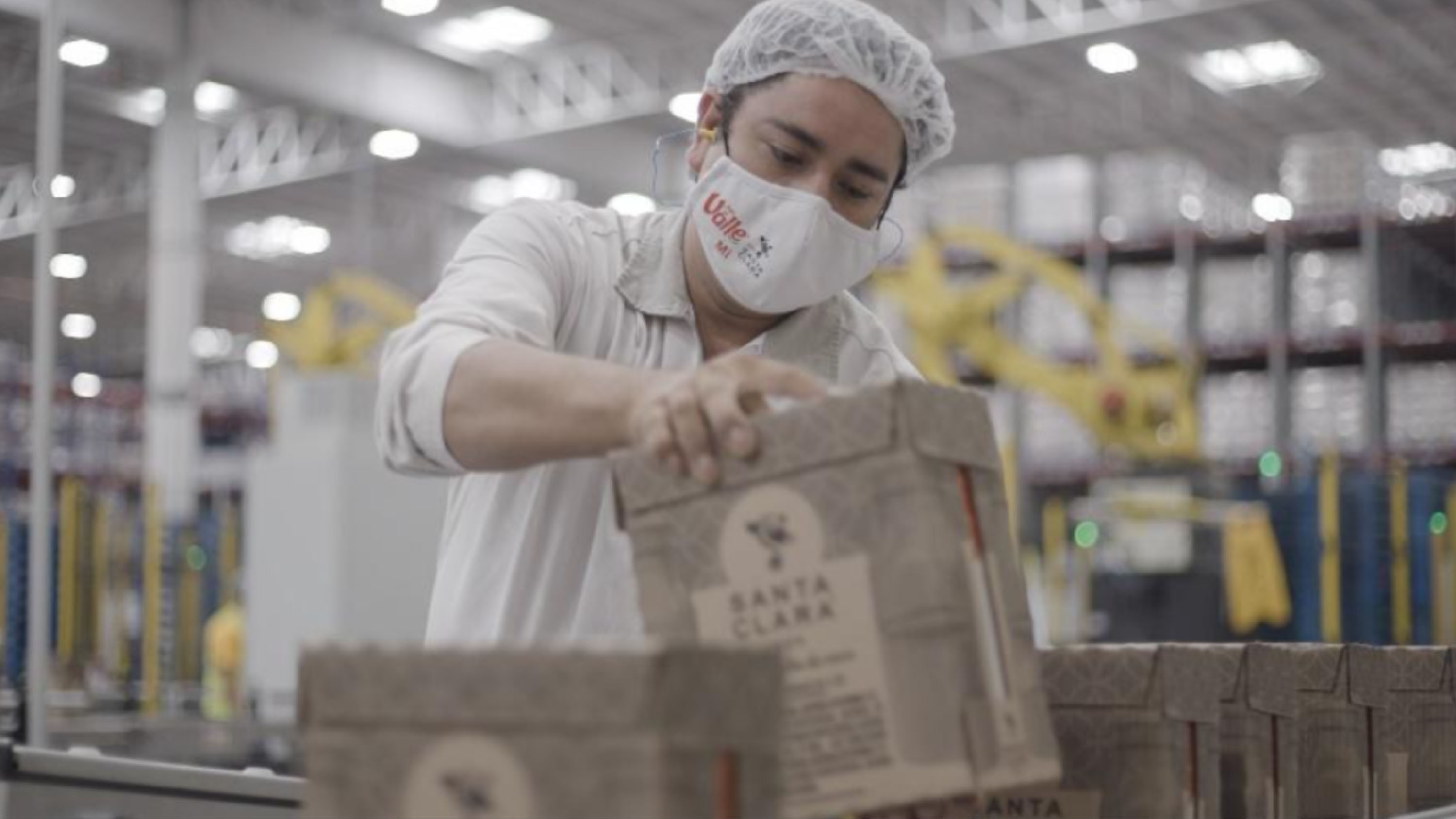 Hombre sosteniendo una caja de productos Santa Clara en una fábrica.