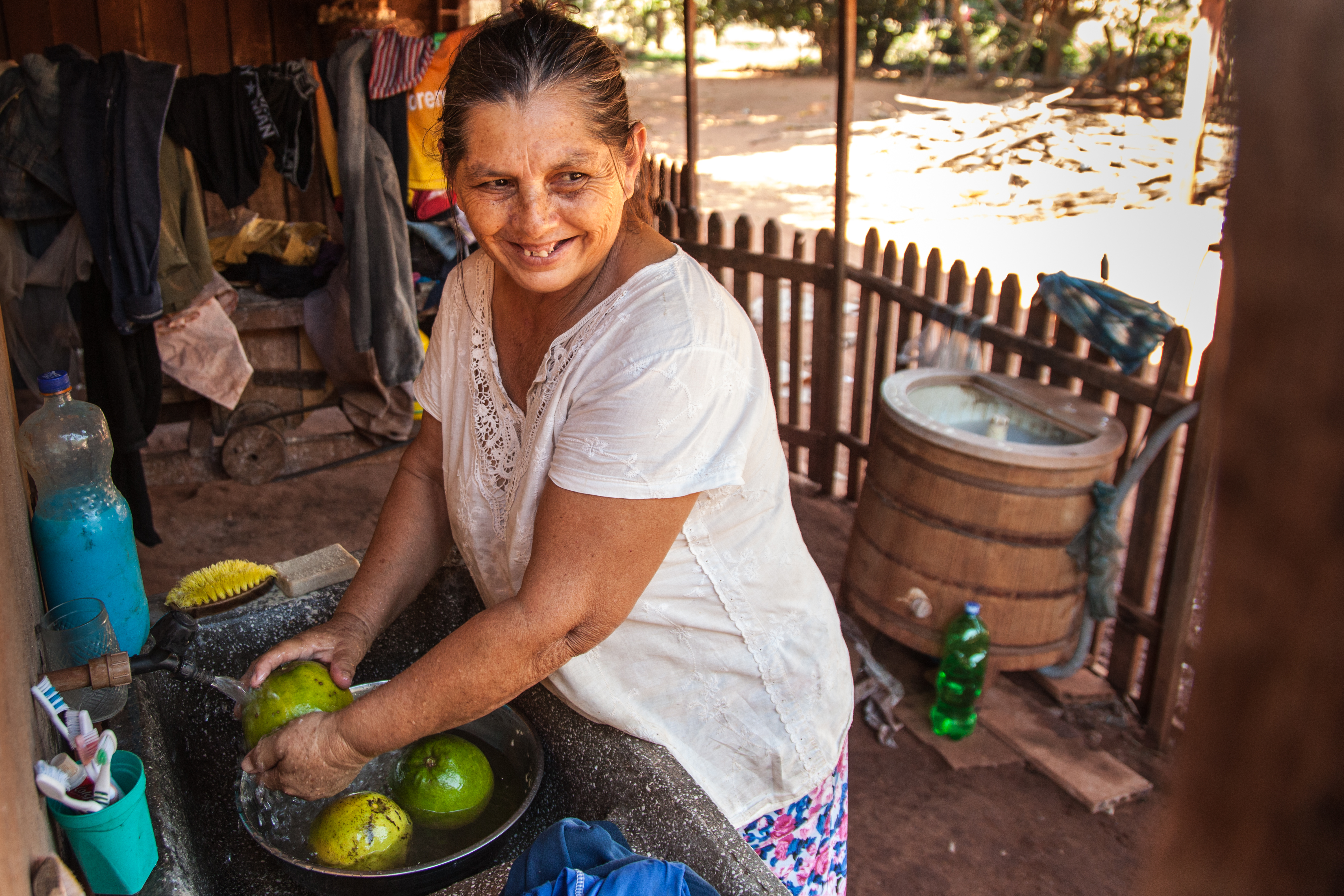 Mujer lavando fruta en un barreño