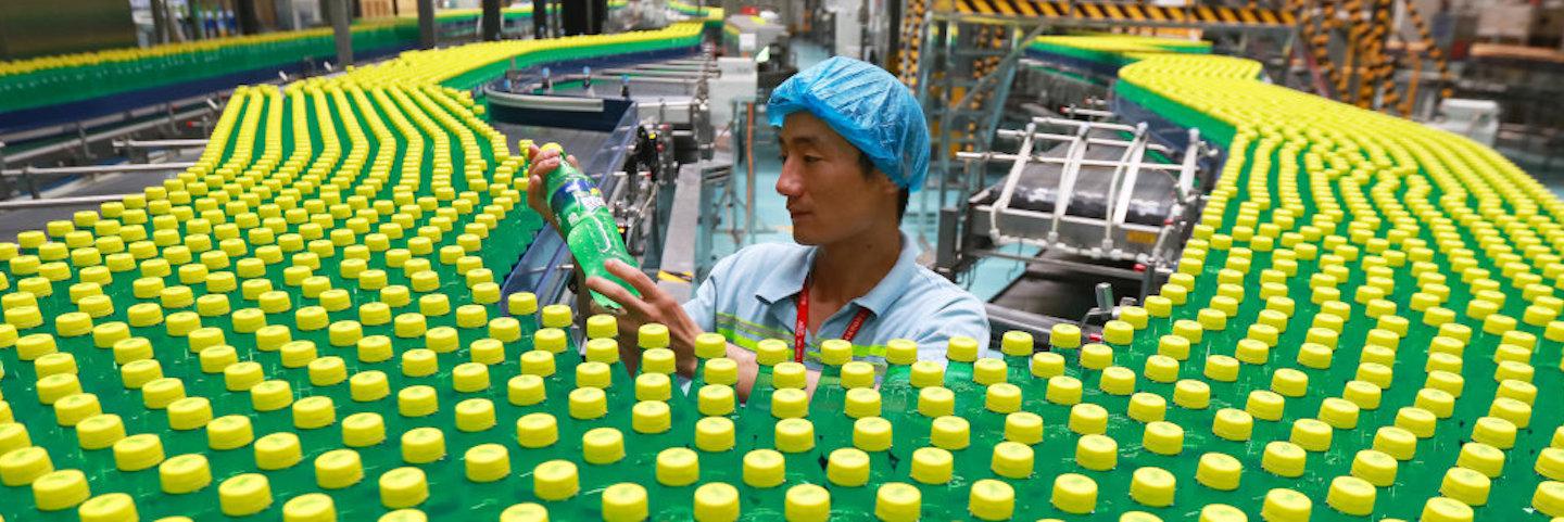 A man working on a factory production line with multiple Sprite bottles