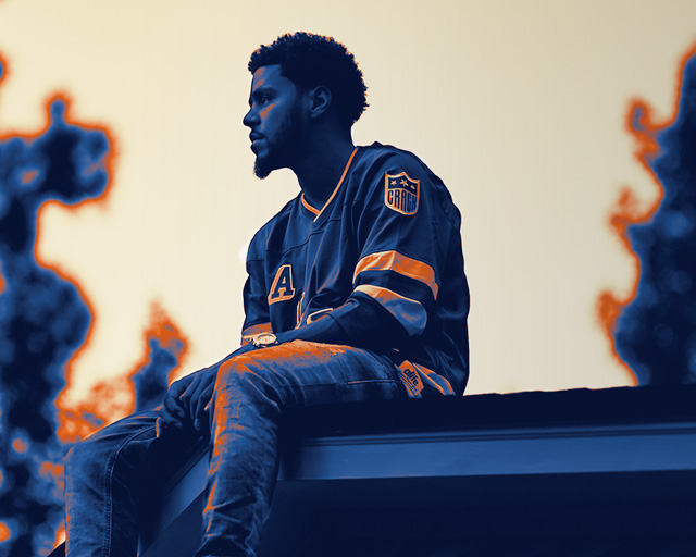 J. Cole sitting outside looking off into the distance