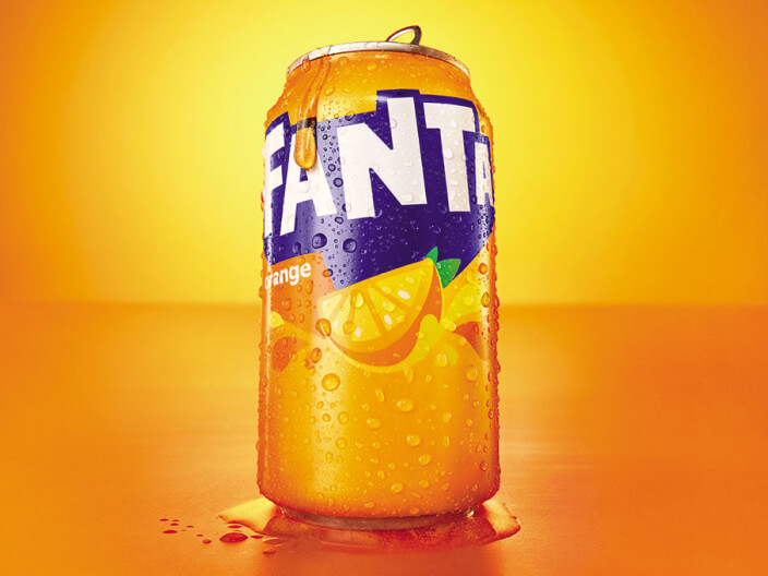 A can of Fanta Orange with condensations dripping down the sides with an orange background