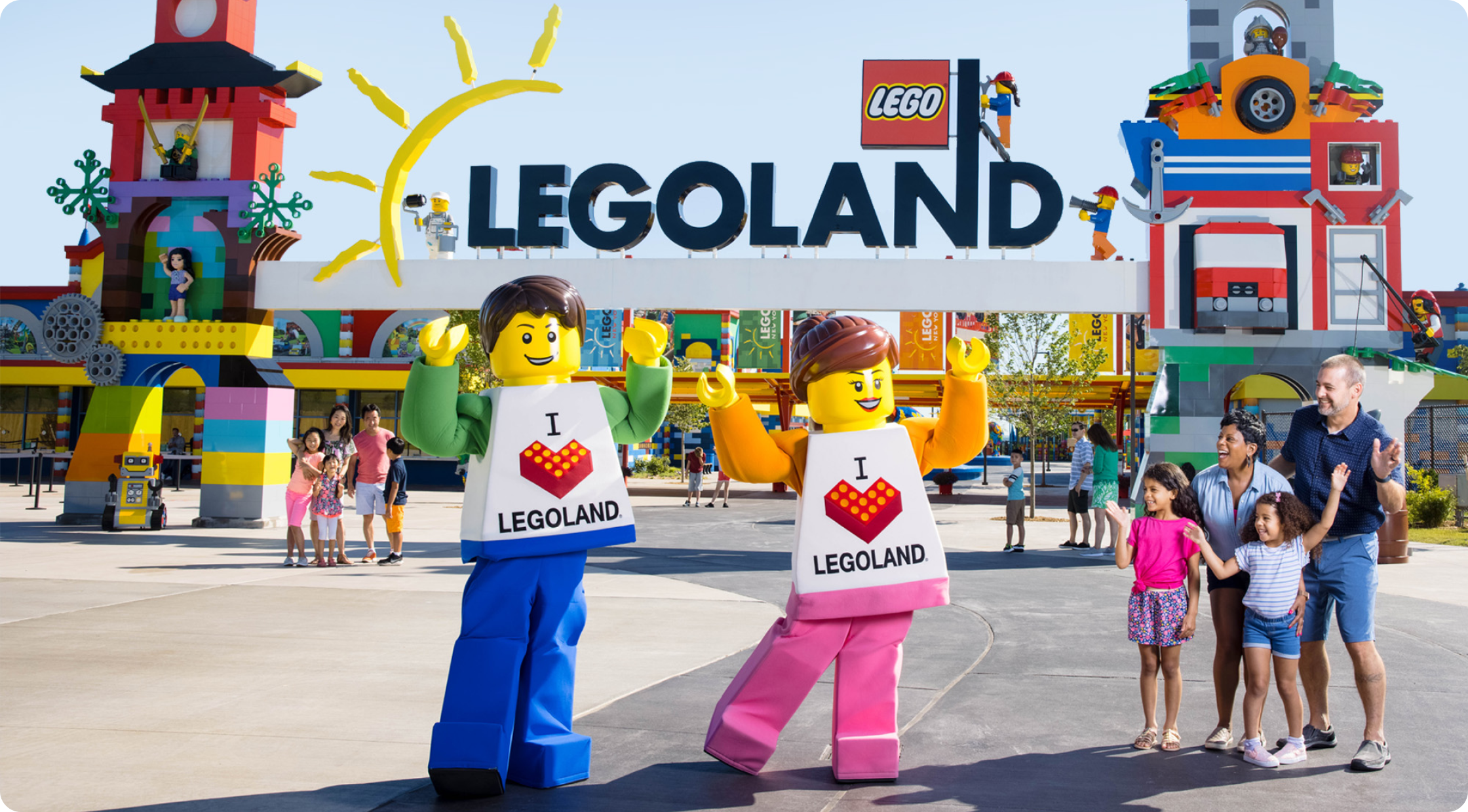 Lego characters standing in front of Legoland entrance next to a family of four