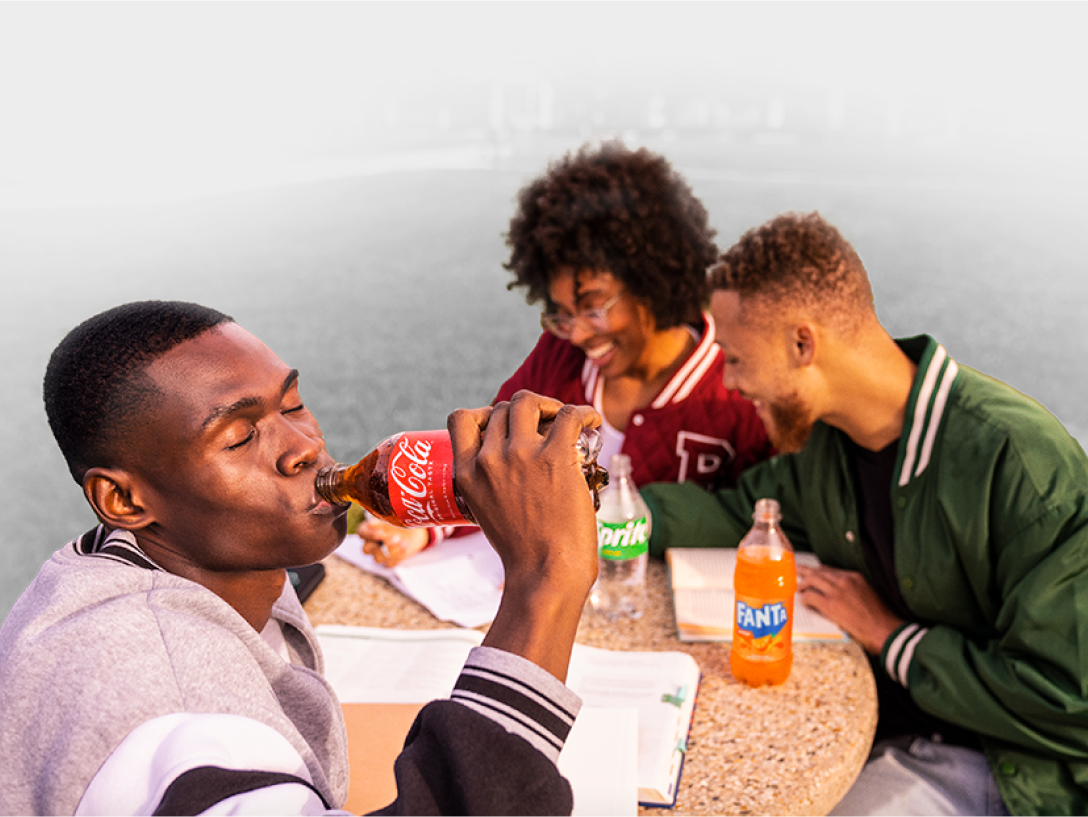 Group of friends sitting outside at a table enjoying Coca-Cola products