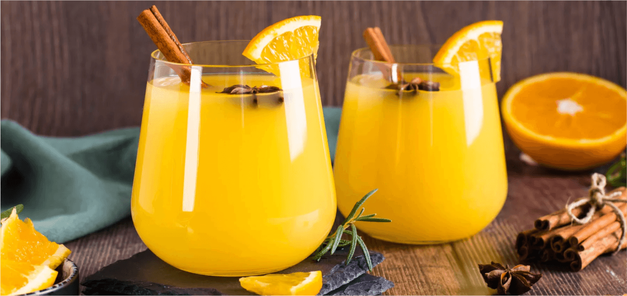 two orange drinks in glasses with cinnamon and orange slices