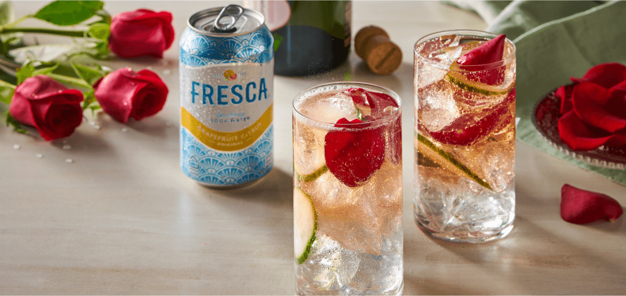 two clear drinks with a hint of orange next to a can of fresca