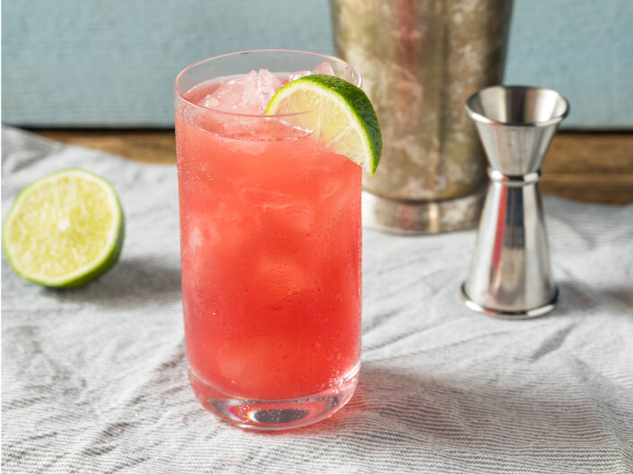 a pinkish peach colored drink with lime