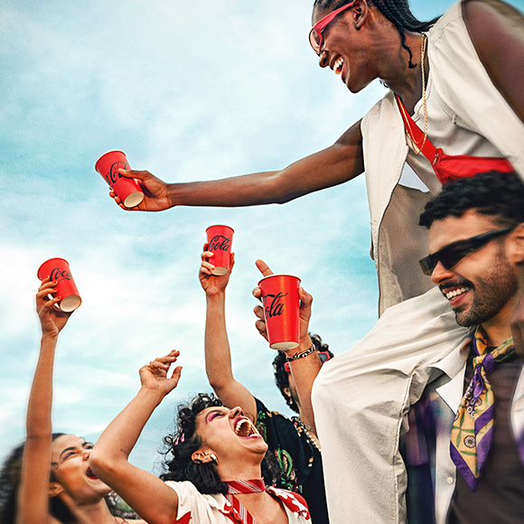 Grupo de jóvenes disfrutando Coca-Cola en un ambiente festivo.